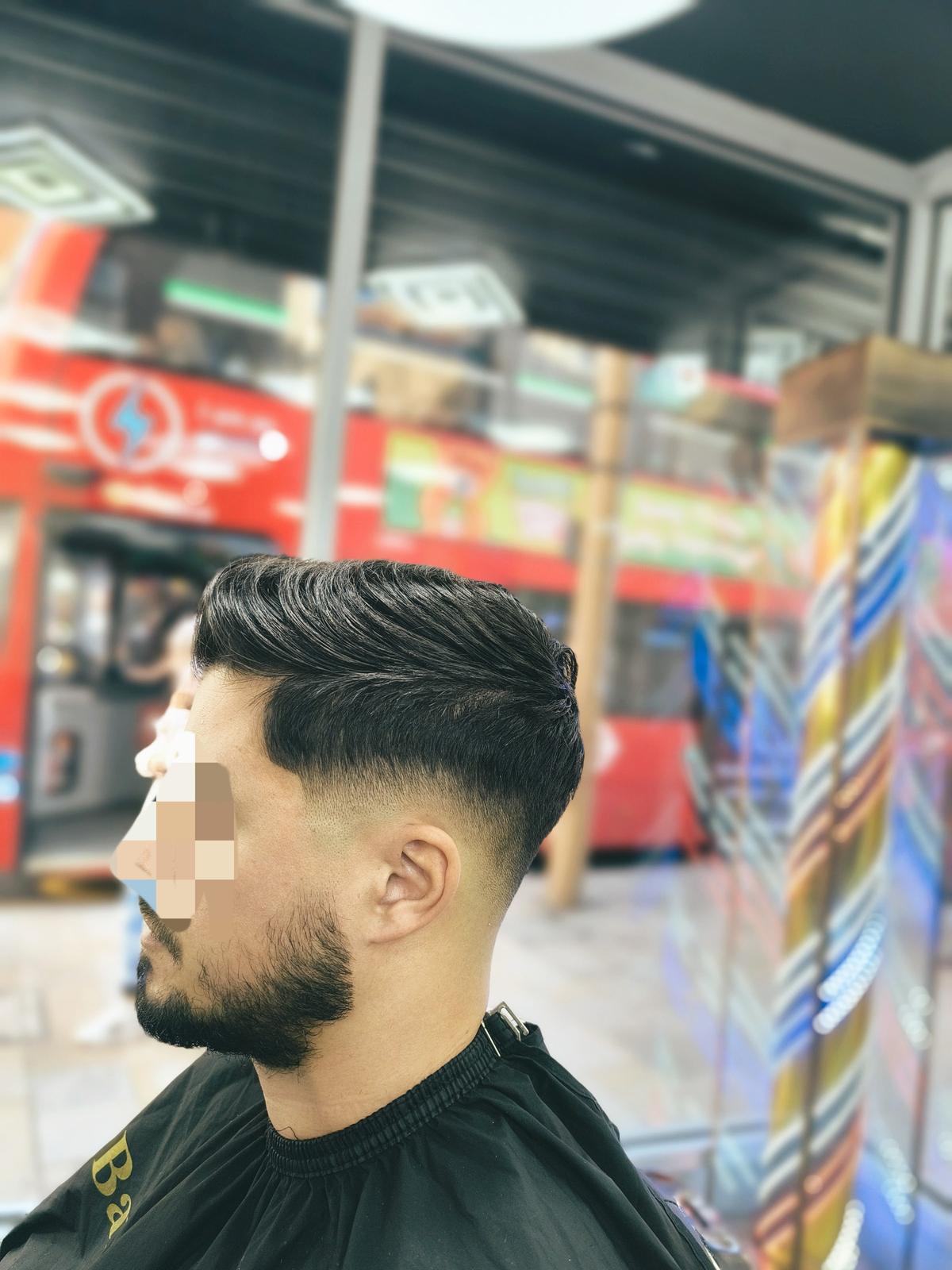 Barber using clippers on a customer's hair