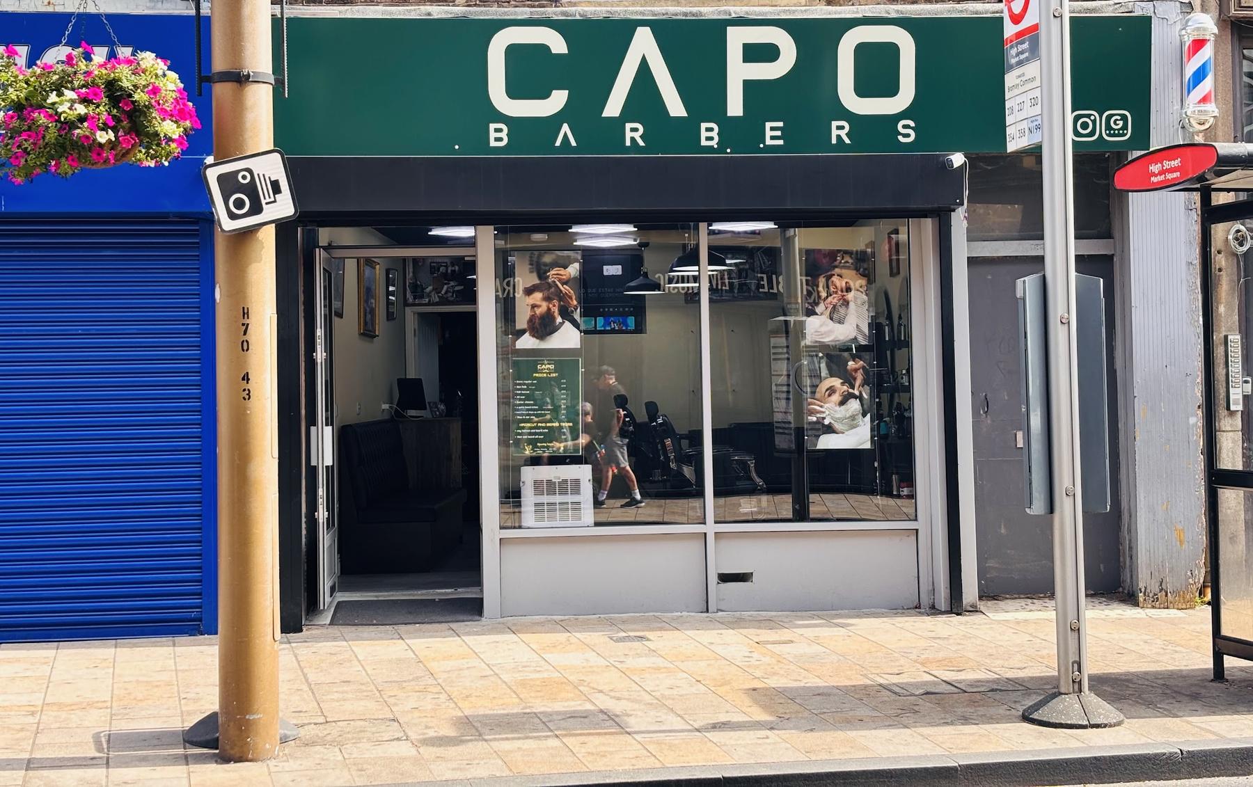 Barber chairs and mirrors in a shop, with a red neon Barber sign